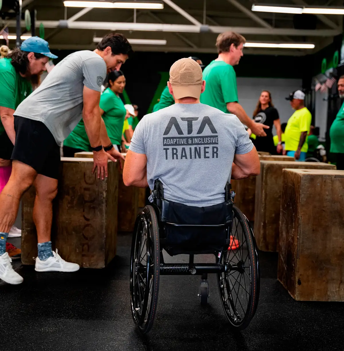 An ATA Adaptive and Inclusive Trainer works out from his wheelchair alongside a group at a box station