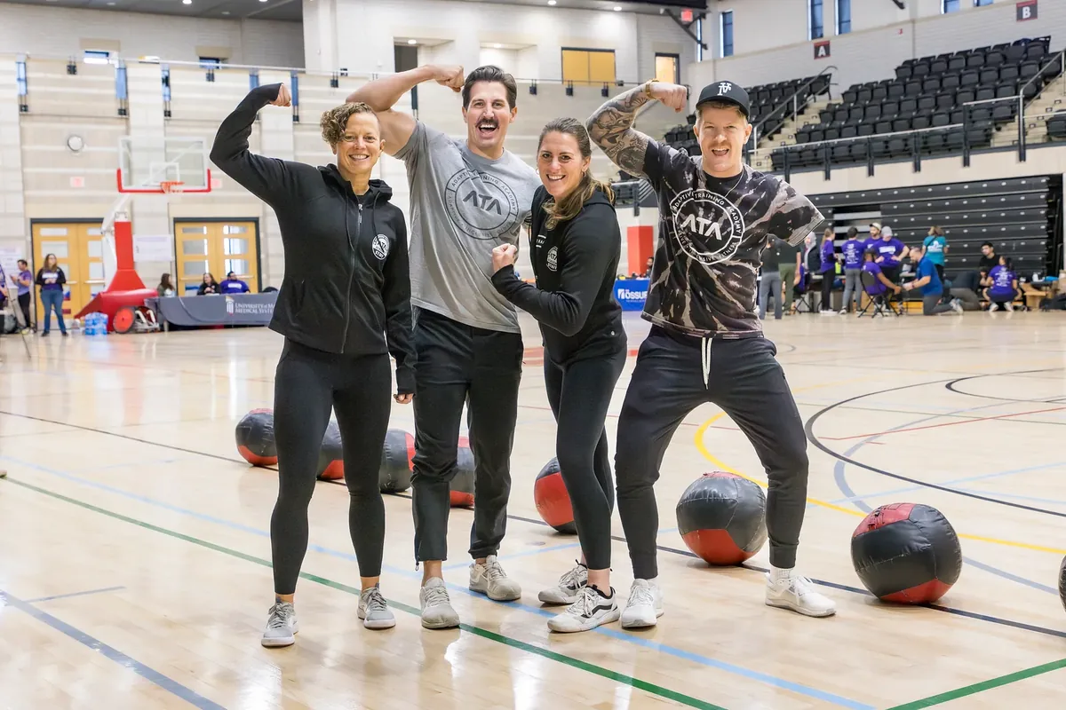 Four ATA trainers and athletes flexing together at a community fitness event