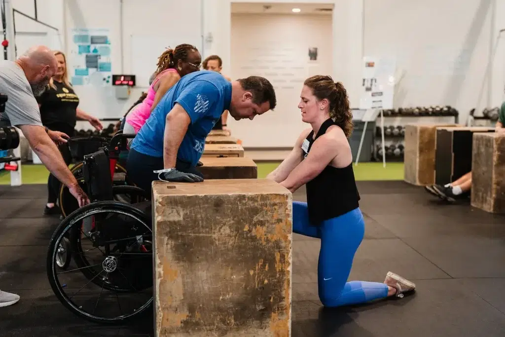 AIT coach Dr. Kiersten McCartney supports an athlete performing dips at an ATA seminar