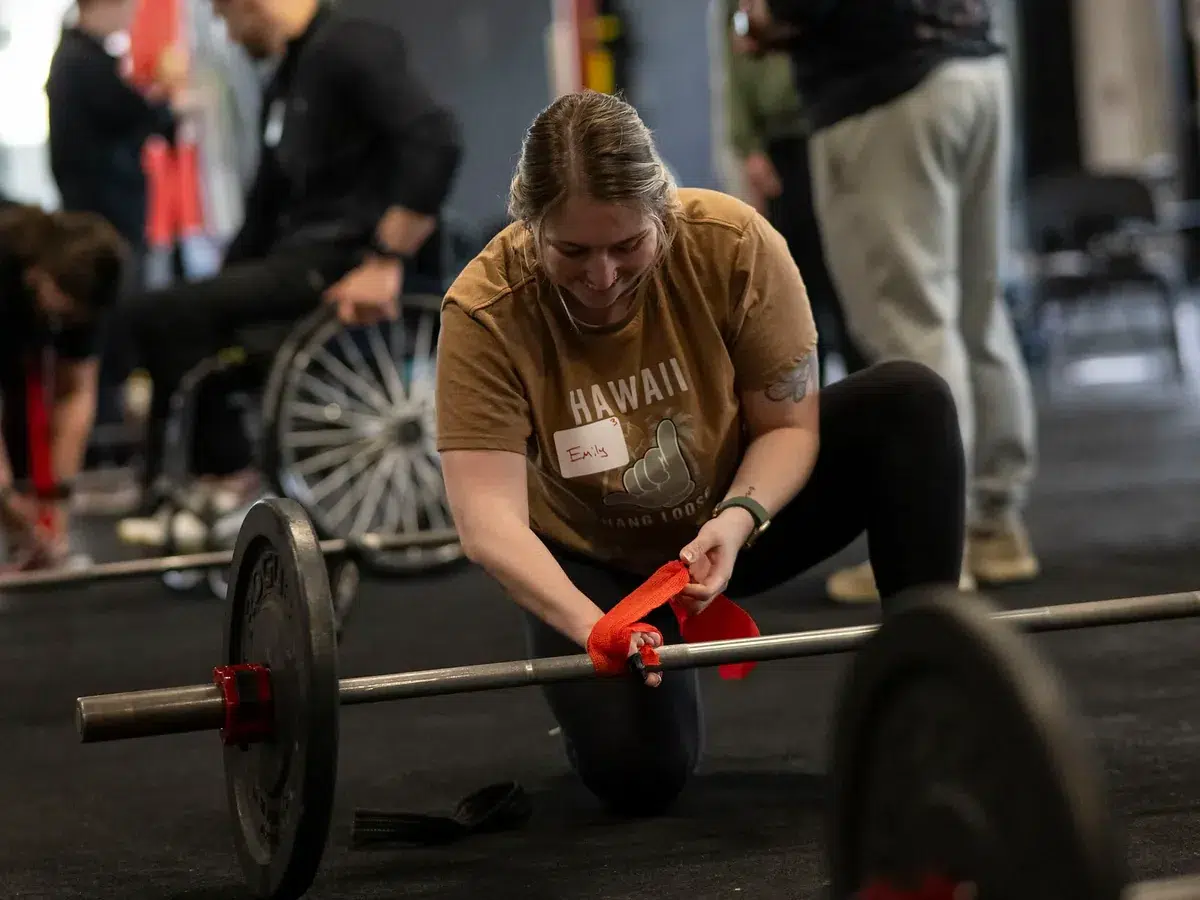 A seminar attendee loads a barbell during an adaptive training workshop