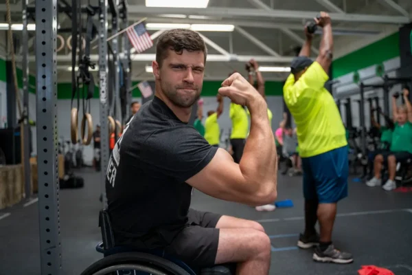 Tom Miazga flexes his biceps from his wheelchair at an ATA training camp for Veterans