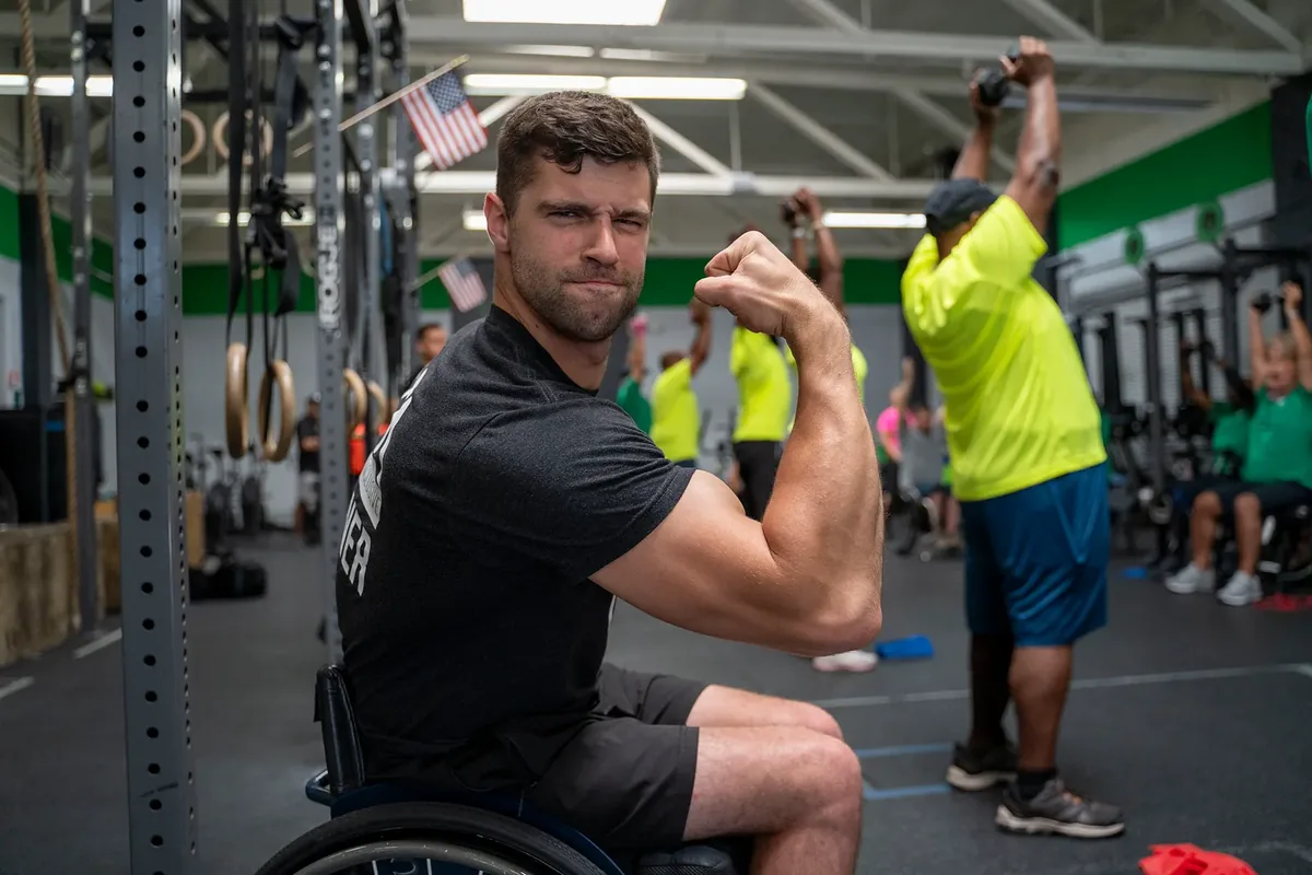 Tom Miazga flexes his biceps from his wheelchair at an ATA training camp for Veterans
