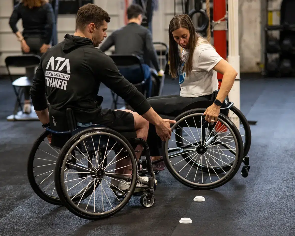 A trainer practises using a wheelchair under the mentorship of an ATA seminar staff member
